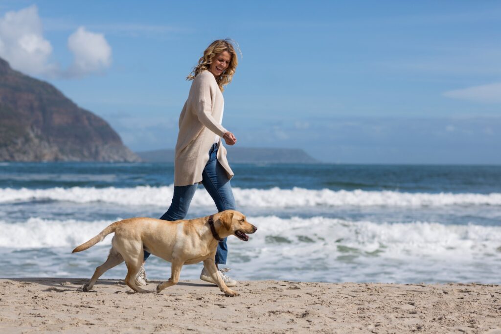 Woman walking with her dog on the beac